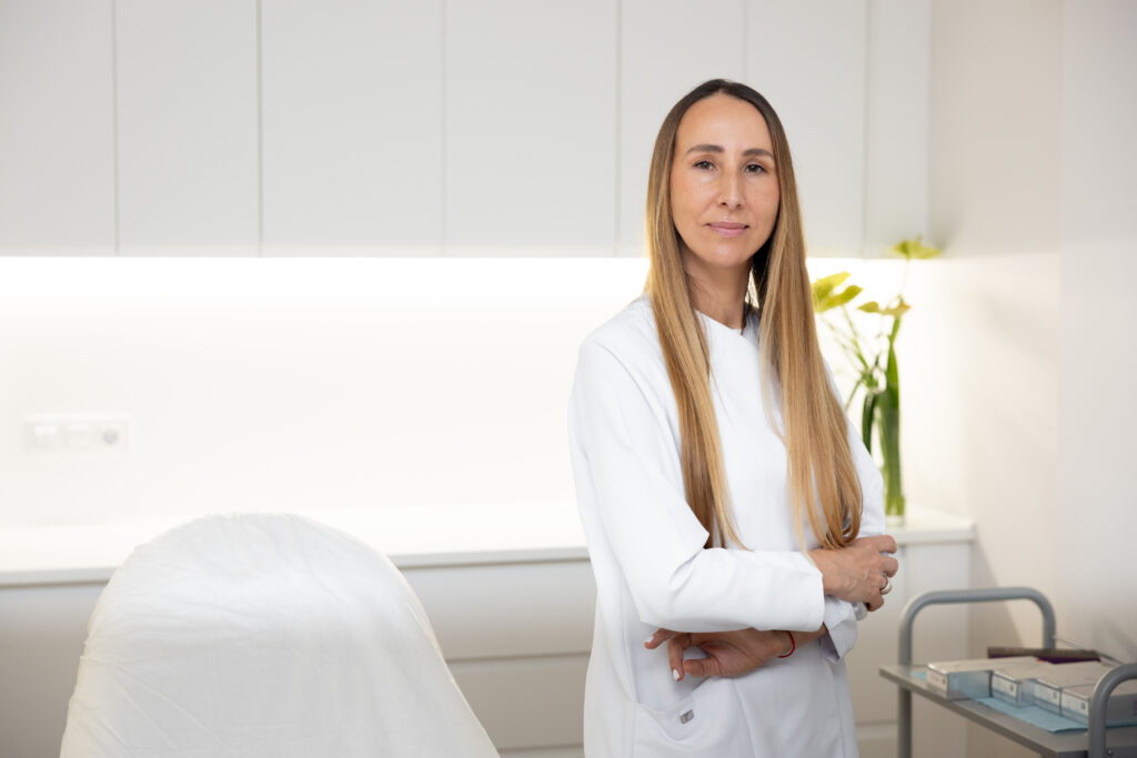 La Dra. Irina Moiseeva sostiene un espejo de Irina Clinic para que una paciente vea el resultado de su tratamiento, en la consulta de Manresa